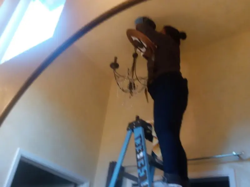 Electrician installing a chandelier in a Sunnyside residence